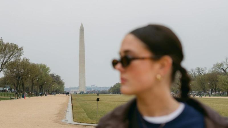 female standing with sunglasses on outside